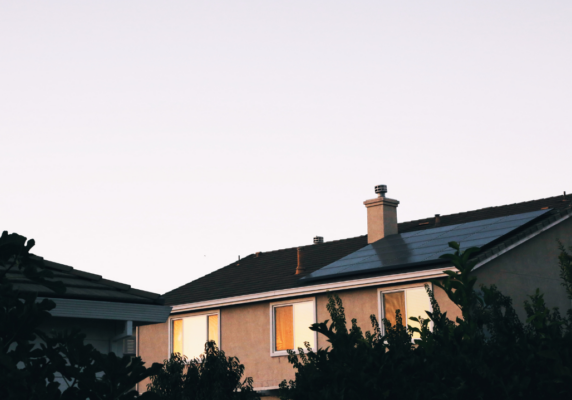 medium close picture of a house at dusk showing windows and trees in front
